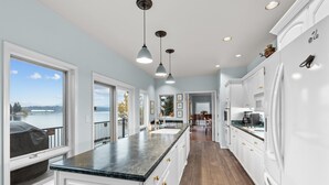 A spacious kitchen with a large island, white cabinetry, and a view of the outdoors.