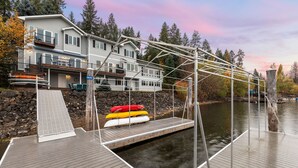 A waterfront property with a dock, kayaks, and a house with a balcony.