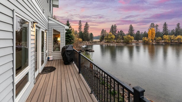 A wooden deck with a view of a lake and trees.