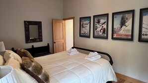 A hotel room with a bed, a wooden door, and posters on the wall.