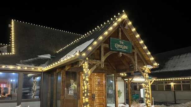 A wooden building with a sign reading 'The Copper Mine Restaurant' at night.