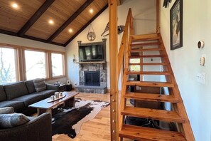 Un salon chaleureux avec une cheminée, un escalier en bois et un canapé.