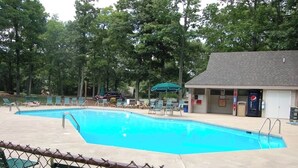 A swimming pool with lounge chairs and a building with a Pepsi vending machine.