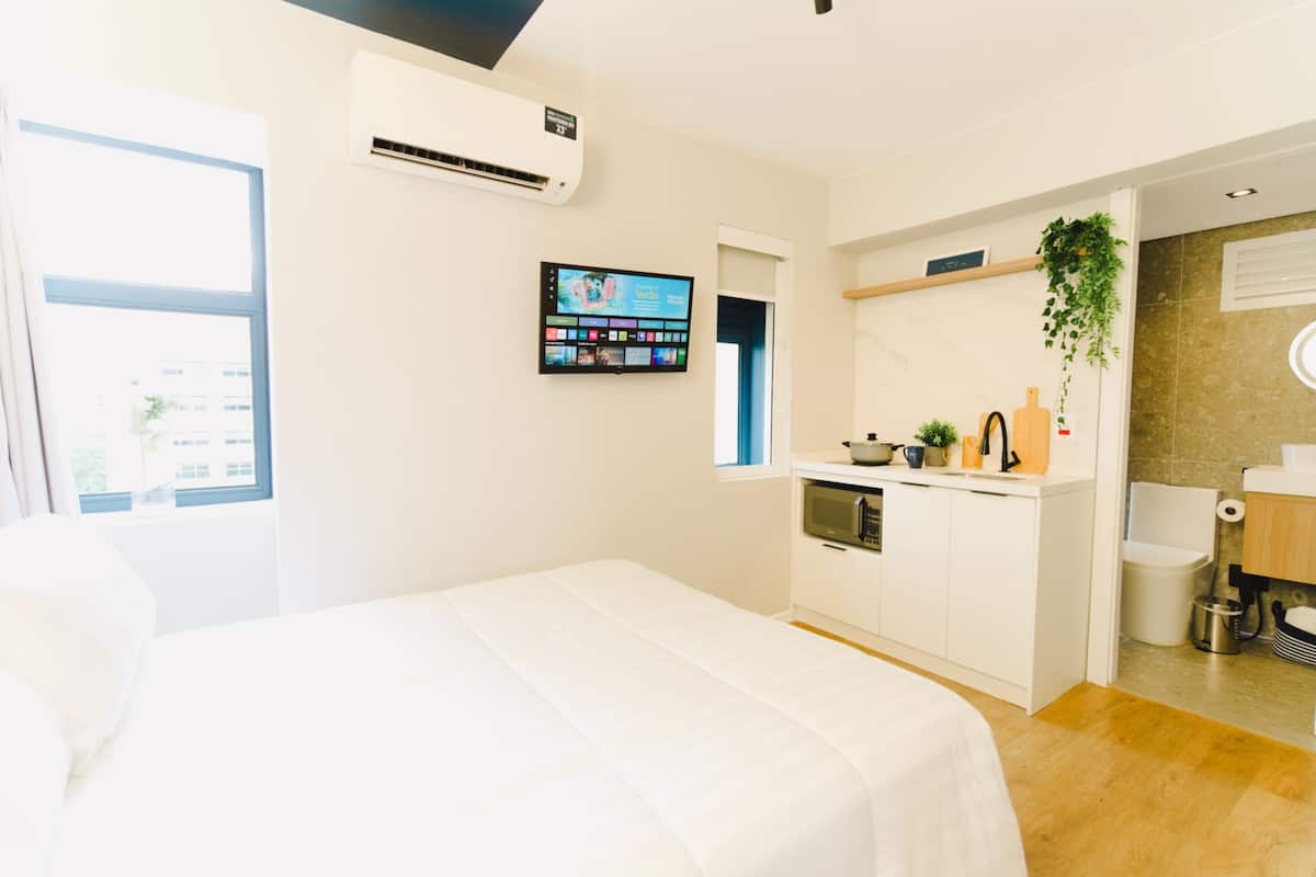 Une chambre d’hôtel moderne équipée d’un lit, d’une petite kitchenette, d’une télévision et d’une salle de bain.