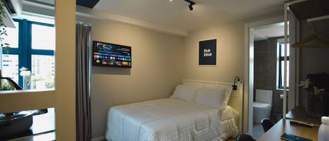 Una habitación de hotel moderna con una cama bien hecha, un televisor de pantalla plana montado en la pared y un letrero que dice "home".