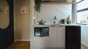 Una cocina moderna con armarios blancos, un lavavajillas negro, un horno empotrado y un ventanal con vistas a la ciudad.