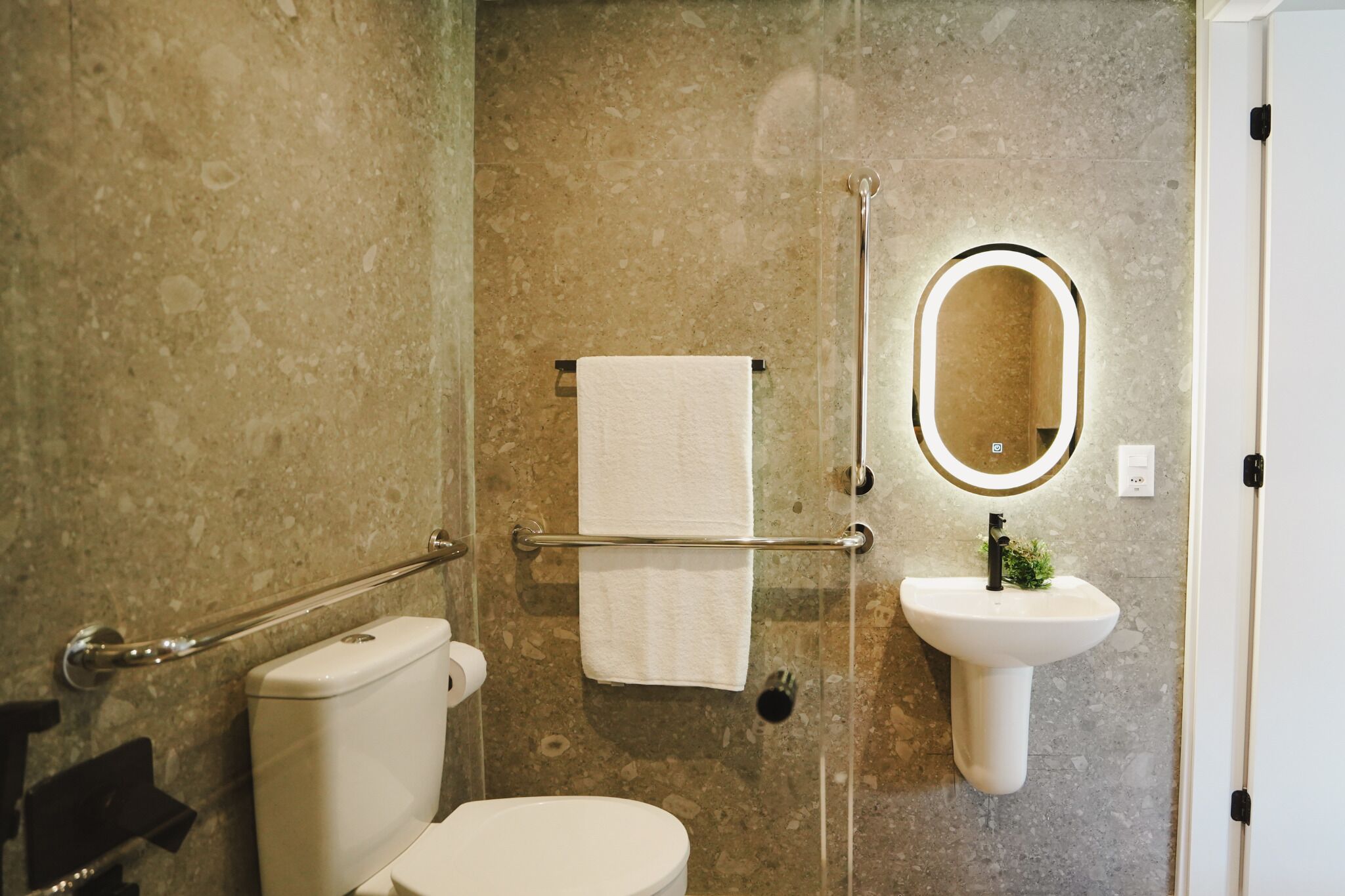 Une salle de bain équipée de toilettes, d’un lavabo, d’un porte-serviettes et d’un miroir.