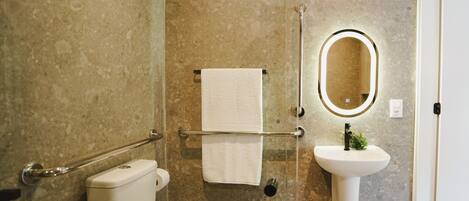 Une salle de bain équipée de toilettes, d’un lavabo, d’un porte-serviettes et d’un miroir.