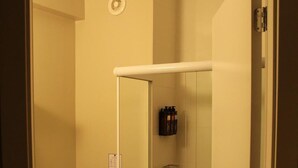 Un baño pequeño con inodoro, cabina de ducha de vidrio y puerta blanca.