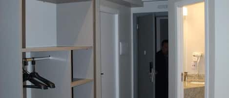 Habitación de hotel con cama, armario, baño con lavamanos y puerta que da a otra habitación.
