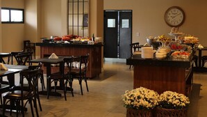 Un comedor de hotel con servicio de buffet, mobiliario de madera y un reloj en la pared.