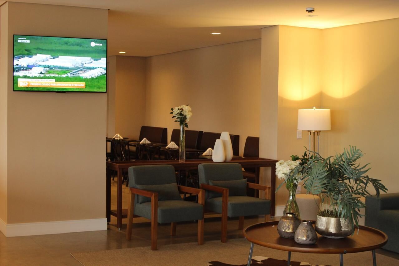 A hotel lobby with a TV, seating area, and a table with vases.