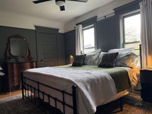 Une chambre à coucher avec un lit, une commode, un miroir et des fenêtres.