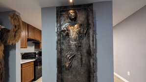 Una habitación con una gran estatua de bronce, armarios de madera, una estufa y un perro.