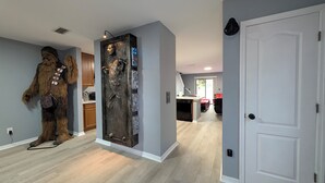 Una cocina moderna con refrigerador empotrado, muebles de madera y un comedor con una silla roja.