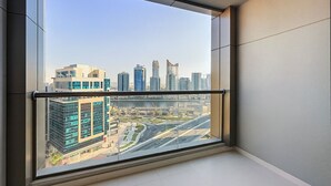 Eine hohe Wohnung mit einem großen Fenster und Blick auf eine Stadtlandschaft, darunter moderne Gebäude und eine Autobahn.