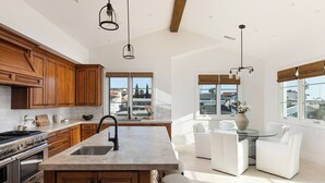 A spacious kitchen with wooden cabinets, a large island, and a dining area with white furniture. - Luxury 3-bedroom house near the pier in San Clemente (San Clemente)