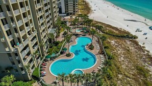 A hotel with a pool, beach, and ocean view.