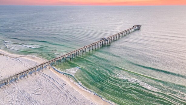A pier extending into the ocean with a beach at its end.
