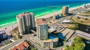 A coastal hotel with multiple high-rise buildings, a beach, and a pier.