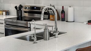 A kitchen with stainless steel appliances, a double sink, and a modern faucet. - Summit Stay | Ground Floor | Central | AC | Pets (Invermere)