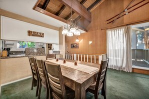 Ein Essbereich mit Holztisch und -stühlen, einer Chandelierleuchtre und Blick ins Freie.