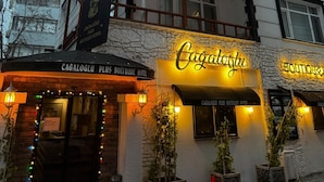 Hotellissa on parveke, ja sen yläpuolella on kyltti, jossa lukee ”Cagaloğlu Plus Boutique Hotel”, sekä neonvalomainos.