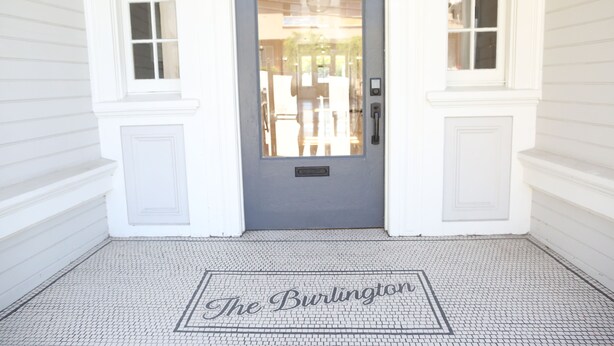 A front entrance with a gray door, white trim, and a tiled floor with "The Burlington" inscription. - The Burlington Hotel (Los Angeles)