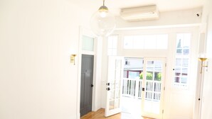 A hallway with wooden flooring, white walls, and a large glass door leading outside. - The Burlington Hotel (Los Angeles)