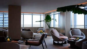 A modern lounge area with comfortable seating, large windows, and a large plant. - AKA Hotel Stunning Views w- Free parking (Miami)