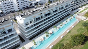 A modern hotel with multiple floors, a rooftop pool, and a landscaped pool area. - Infinity Homes Punta Cana (Punta Cana)