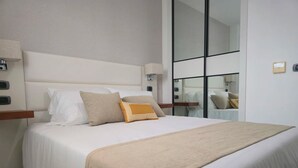 A modern hotel room with a large bed, a mirror, and a nightstand. - Infinity Homes Punta Cana (Punta Cana)