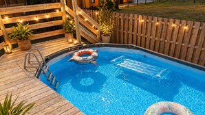 Ein Swimmingpool mit Holzterrasse, einer Leiter und aufblasbaren Ringen.