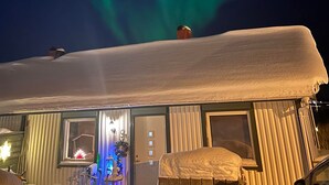 Een huis met een met sneeuw bedekte nok en een raam met verlicht interieur.