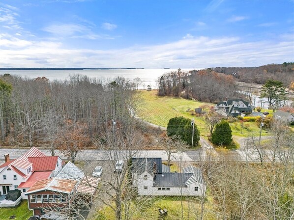 A residential area with houses, a road, and a body of water in the background.