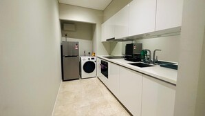 A modern kitchen with a stainless steel refrigerator, a built-in washing machine, and a sink with a faucet. - Sky premium suites klcc (Kuala Lumpur)