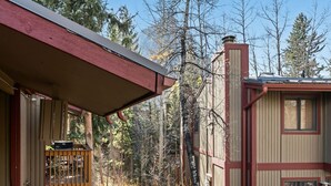 A cabin with a porch, a chimney, and a view of the surrounding forest. - Mountain Charmer | Steps to Main St & Trails (Frisco)