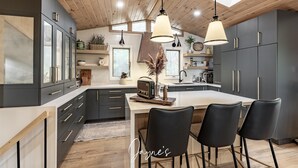 A modern kitchen with dark cabinets, a central island, and pendant lighting. - Delightful 4 bed 2 bath on Bass Lake (MacTier)