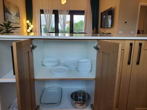 Una cucina con mobili in legno, un espositore per piatti in vetro e una pentola in acciaio inossidabile.