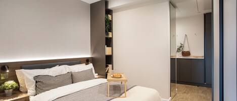 A modern bedroom with a bed, bedside table, and a small table with a plate of food.
