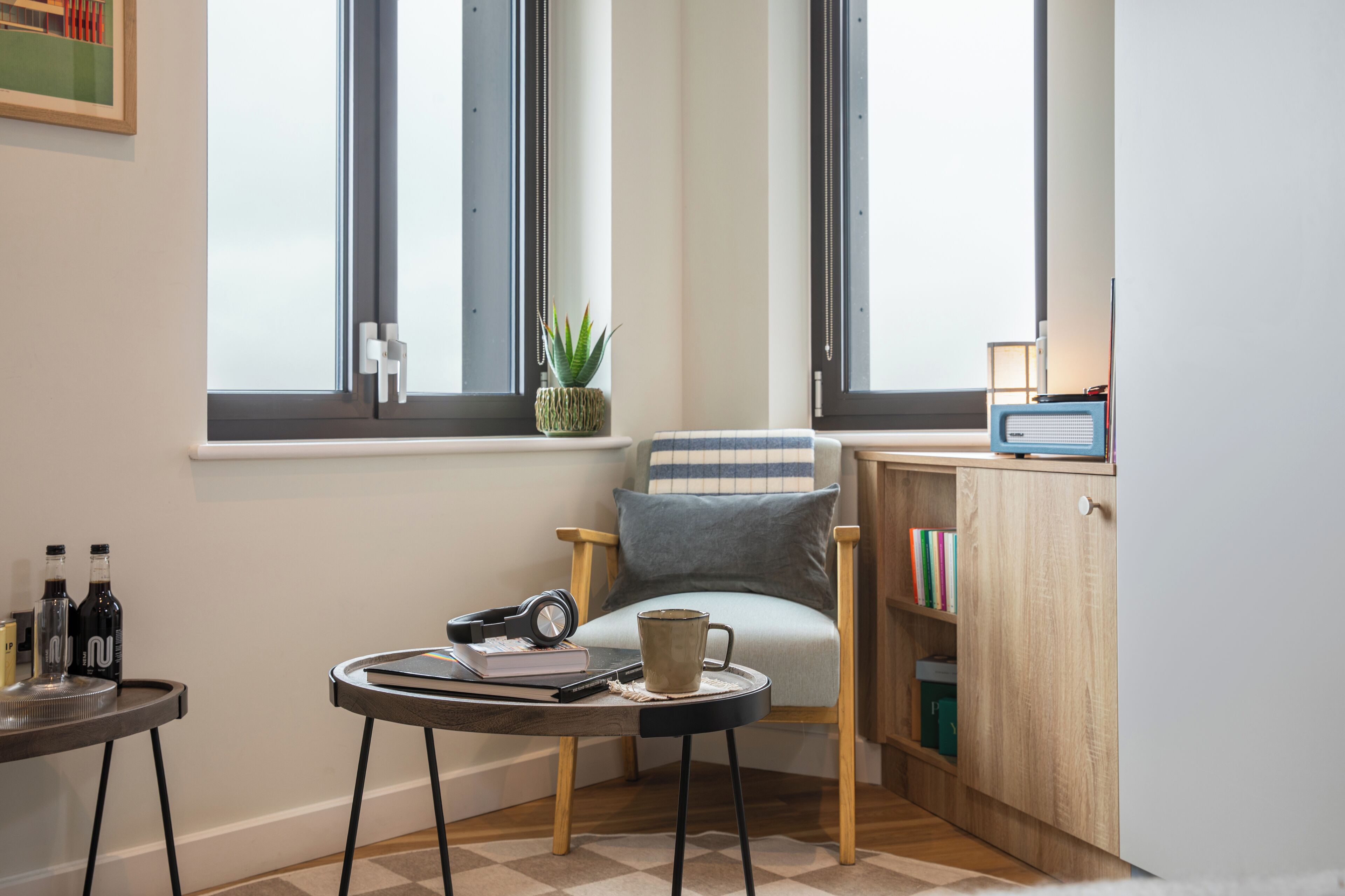 A cozy reading nook with a chair, a small table, and a bookshelf.