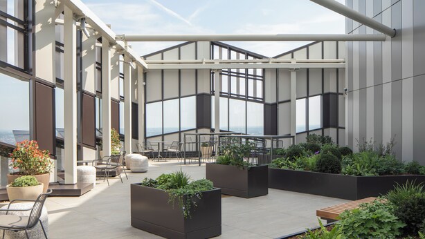 A rooftop terrace with outdoor seating, planters, and large windows offering views. - Enclave Croydon - Campus Accommodation (Croydon)
