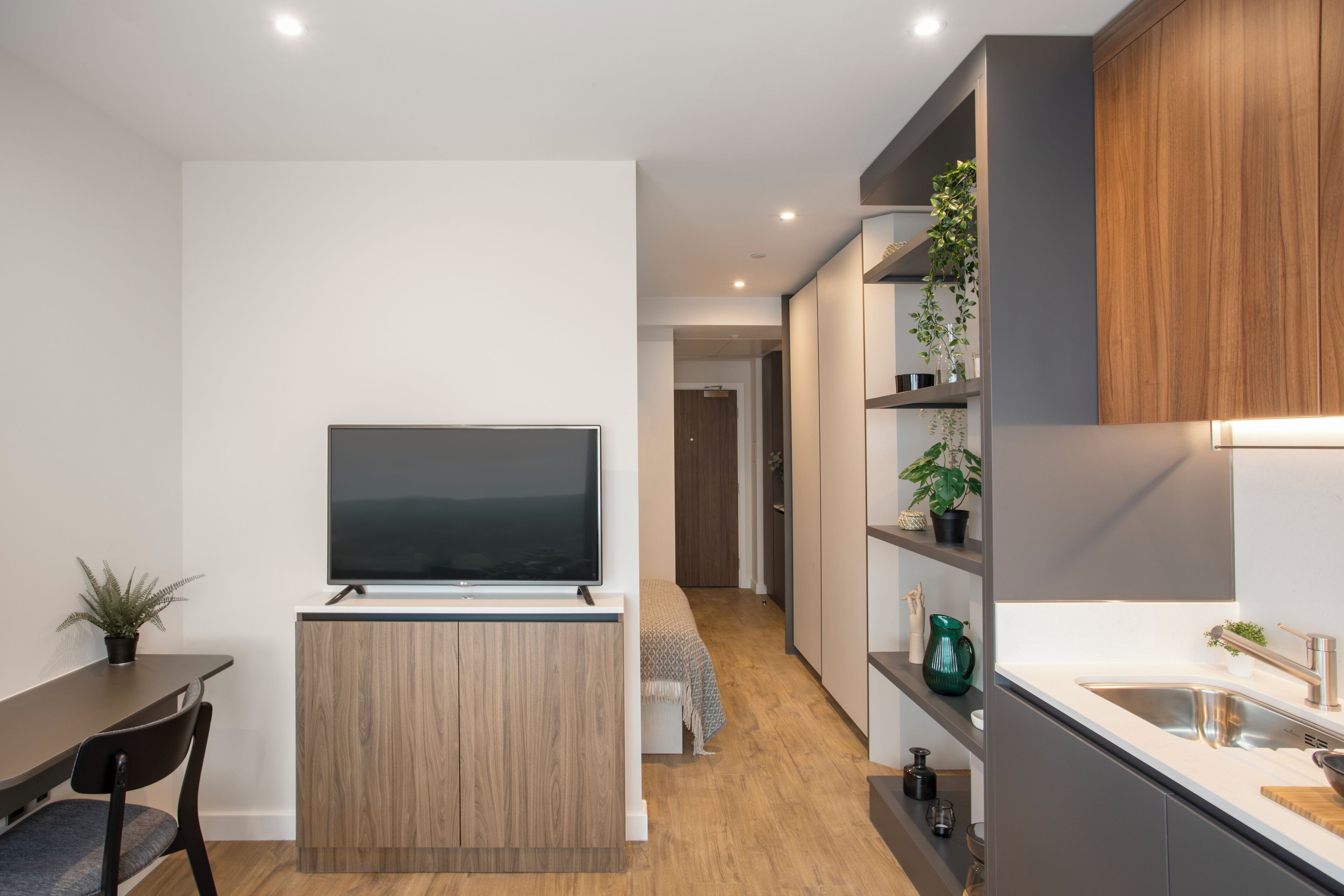 Una cocina moderna con televisión integrada, armarios de madera y una encimera con lavabo.