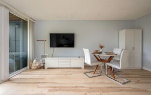 A modern living room with a flat-screen TV, white furniture, and a sliding glass door. - Delightful apartment with AC in charming Lake Oswego (Lake Oswego)