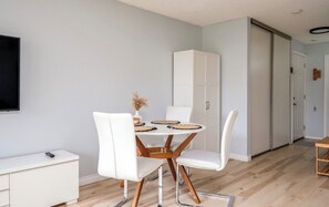 Ein moderner Essbereich mit einem runden Tisch, weißen Stühlen und einem weißen Schrank.