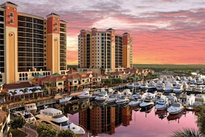 A marina with numerous boats docked, surrounded by multi-story buildings with balconies. - Palm Beach Landings A107 (Fort Myers)