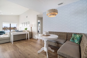 Un salon moderne avec un canapé blanc, une table ronde, un lampadaire et un mur décoré d’un motif.