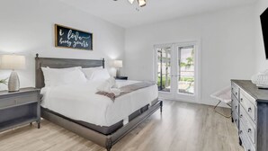 A bedroom with a bed, two bedside tables, a ceiling fan, a window with blinds, and a dresser. - 4213 SW 26th Ave (Cape Coral)