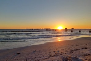A beach with a wooden pier extending into the ocean at sunset. - 207 SE 17th St (Cape Coral)