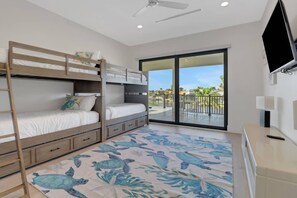 A bedroom with a bunk bed, a desk, a TV, and a balcony with a view. - 2416 SW 49th Ter (Cape Coral)